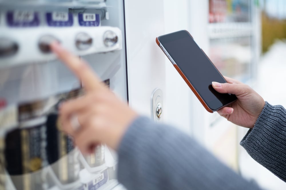 Woman use of soft drink vending system paying by cellphone | ESB Professional / Shutterstock 